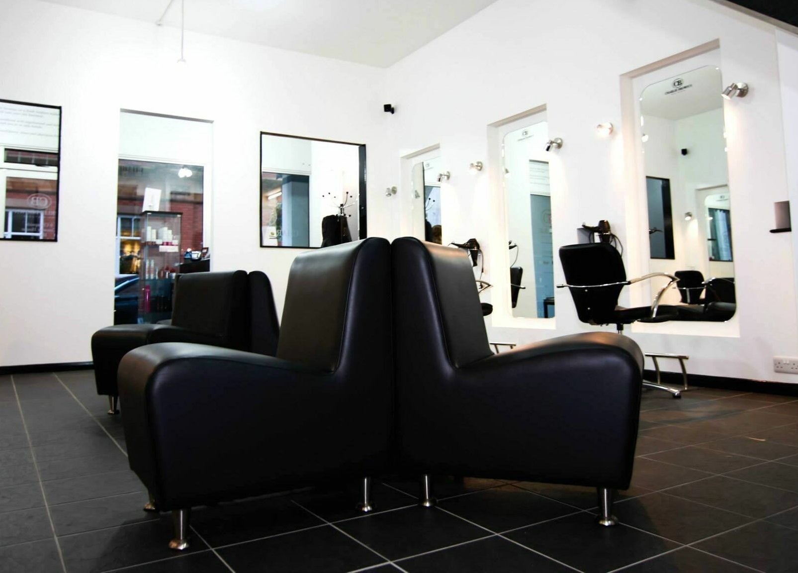 Modern interior of Charlie Browns Hair Studio Ltd in Stoke-on-Trent, England, GB with sleek black seating.