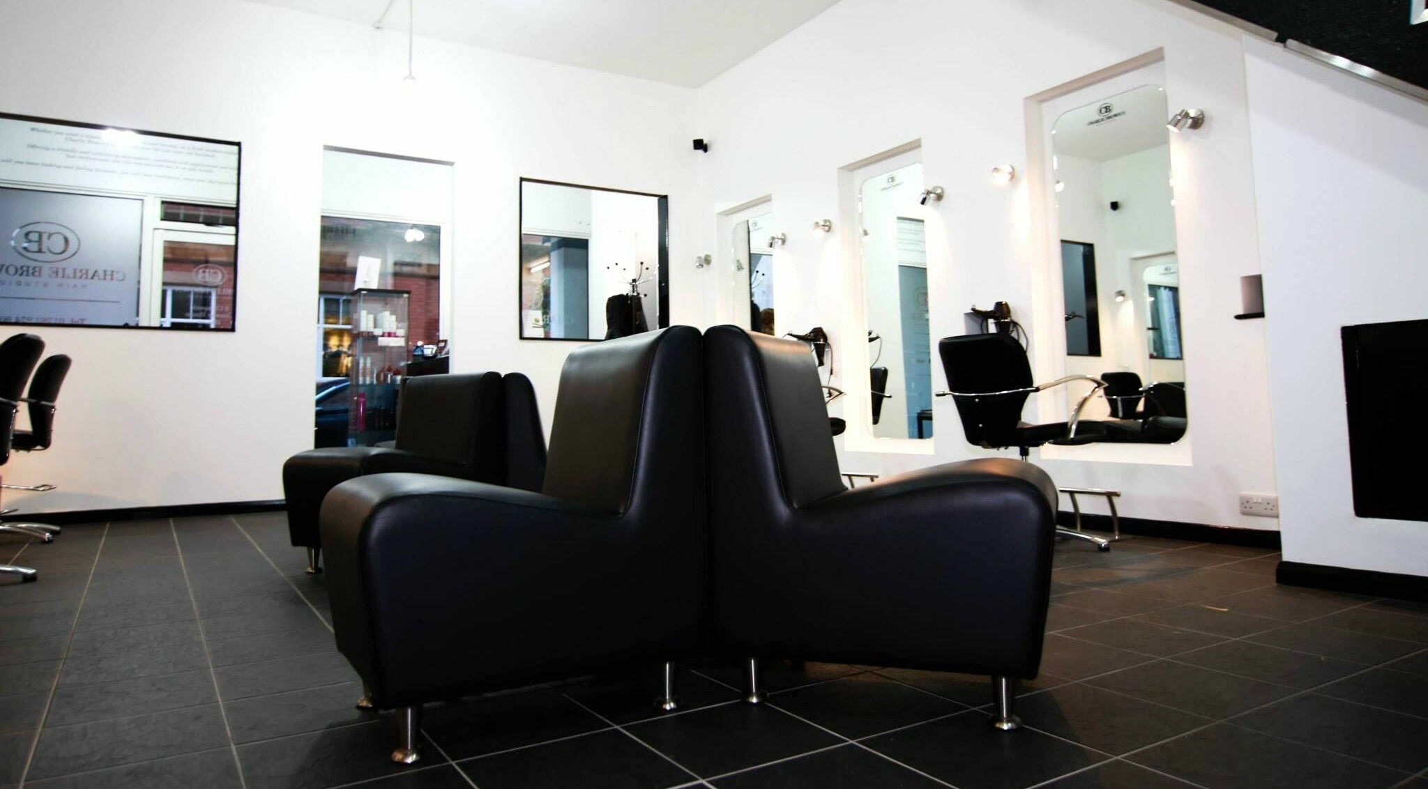 Modern interior of Charlie Browns Hair Studio Ltd in Stoke-on-Trent, England, GB with sleek black seating.