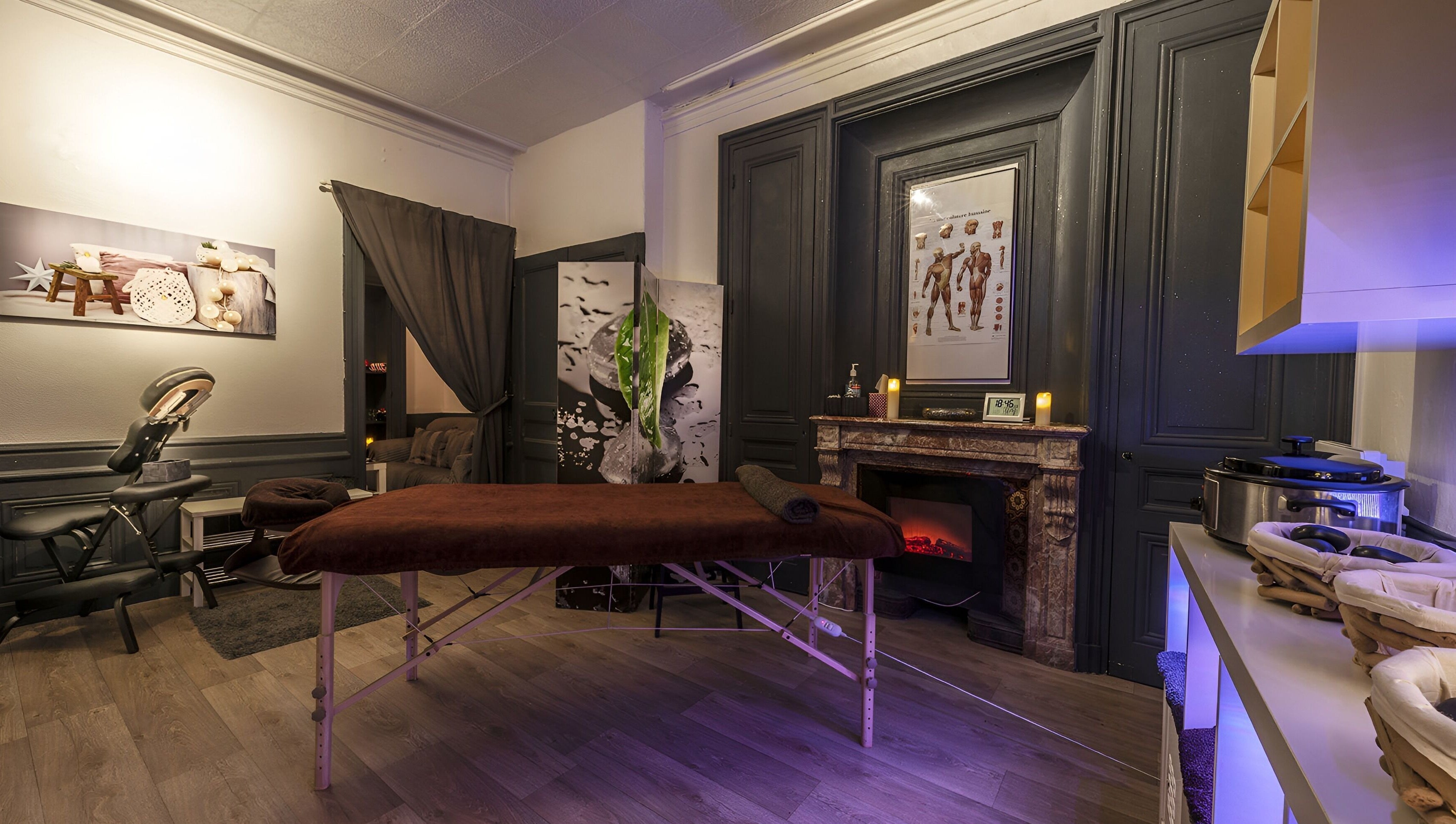 Intérieur relaxant de Perle du Monde Bien-être à Lyon, Auvergne-Rhône-Alpes, avec table de massage et cheminée.