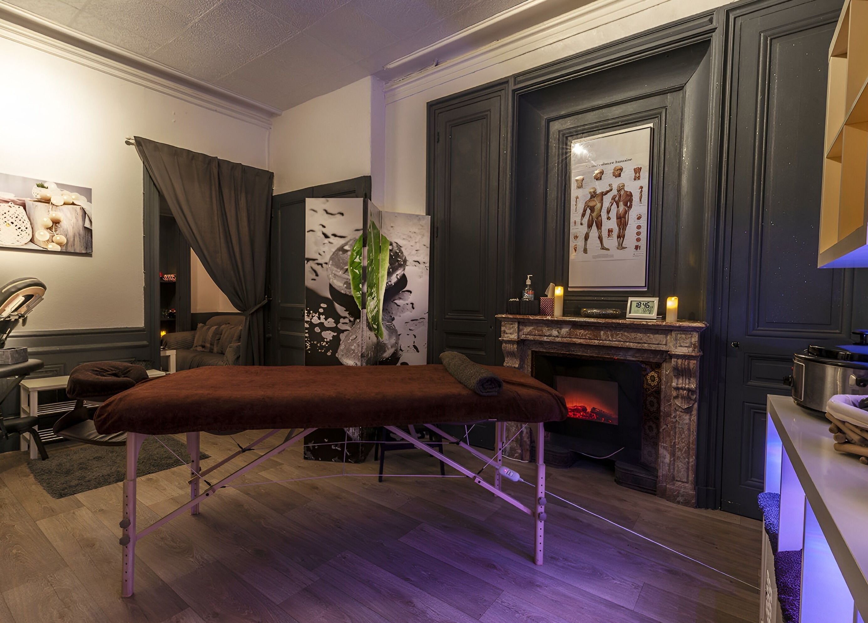 Intérieur relaxant de Perle du Monde Bien-être à Lyon, Auvergne-Rhône-Alpes, avec table de massage et cheminée.