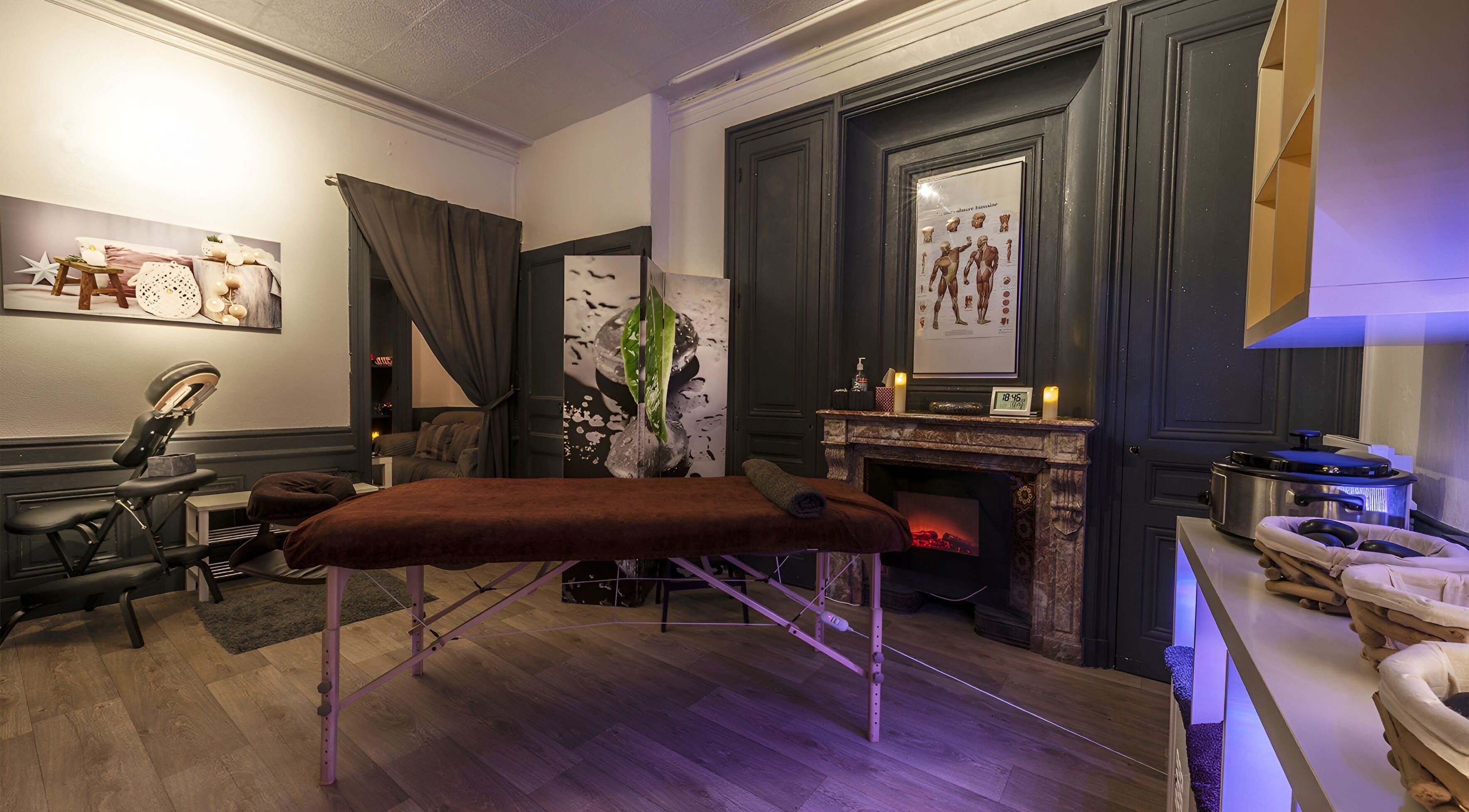 Intérieur relaxant de Perle du Monde Bien-être à Lyon, Auvergne-Rhône-Alpes, avec table de massage et cheminée.