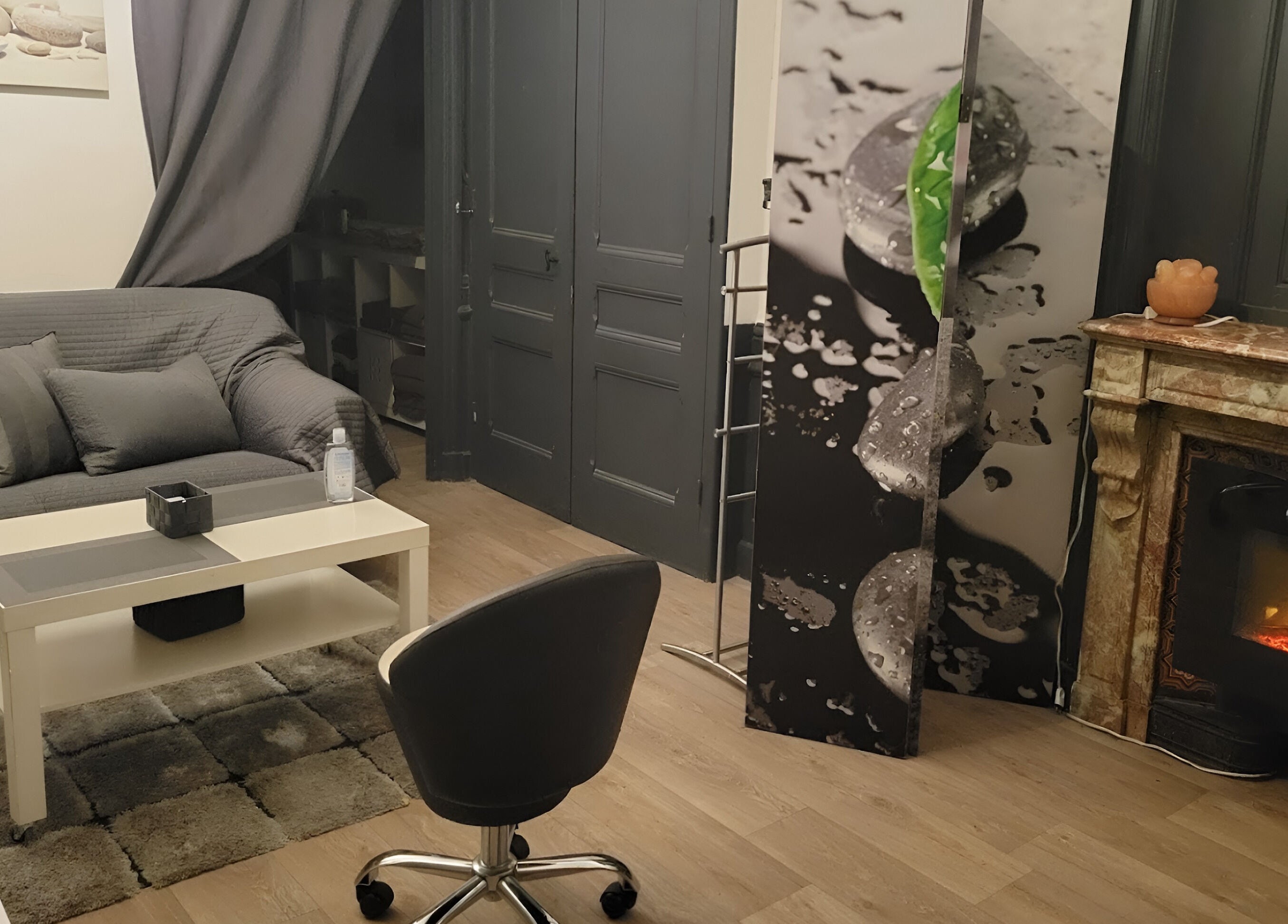 Intérieur élégant du salon Perle du Monde Bien-être, Lyon, avec canapé et cheminée.