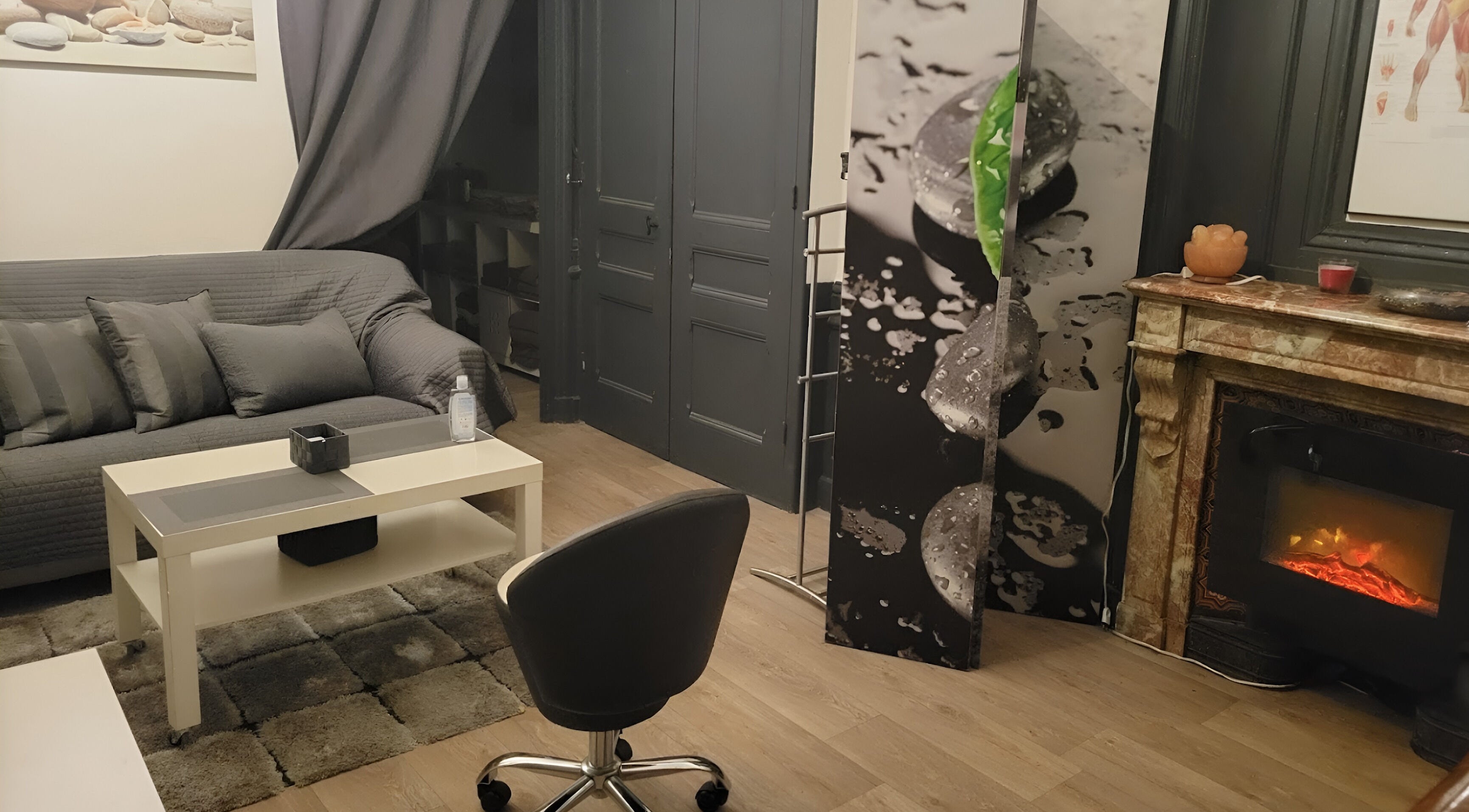 Intérieur élégant du salon Perle du Monde Bien-être, Lyon, avec canapé et cheminée.