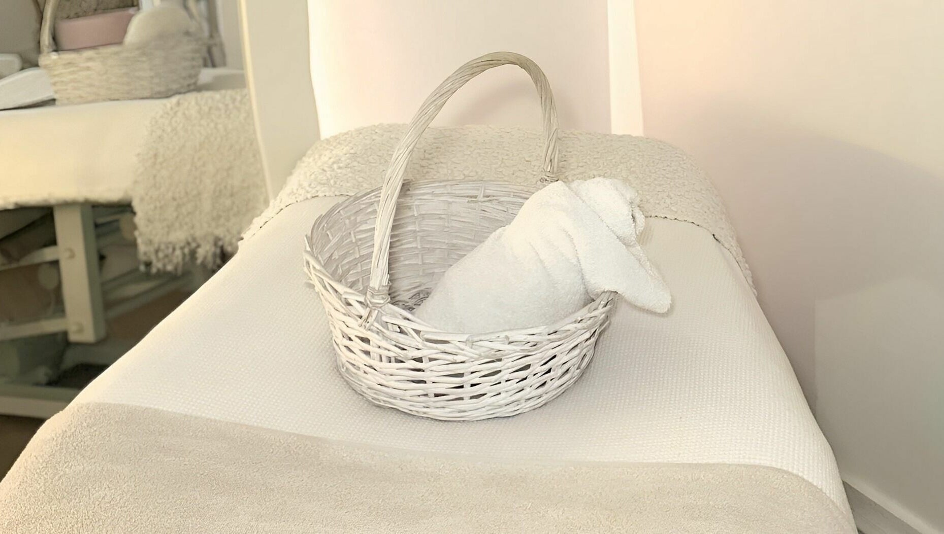 A cozy treatment bed with a white towel in a basket at Skinn Haven, Penrith, New South Wales, AU.