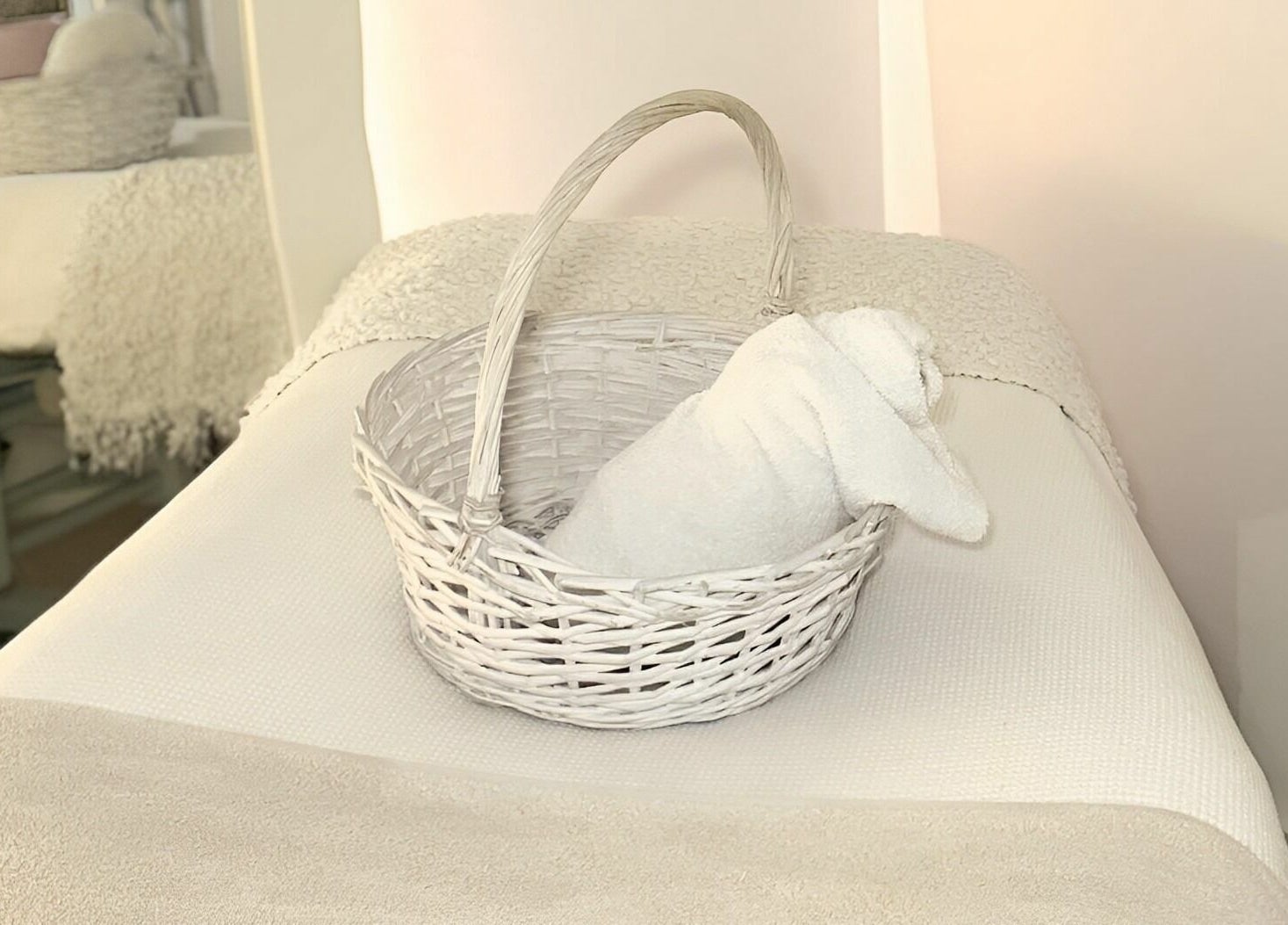 A cozy treatment bed with a white towel in a basket at Skinn Haven, Penrith, New South Wales, AU.