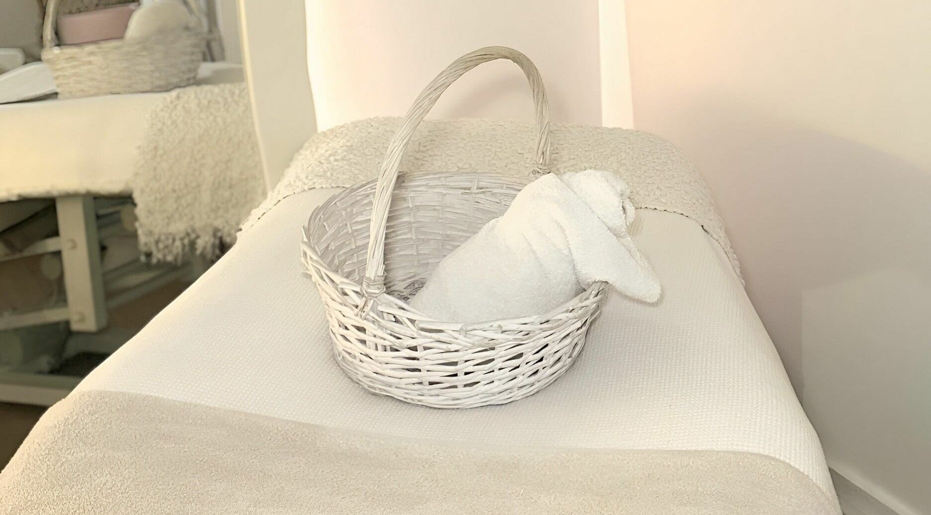 A cozy treatment bed with a white towel in a basket at Skinn Haven, Penrith, New South Wales, AU.