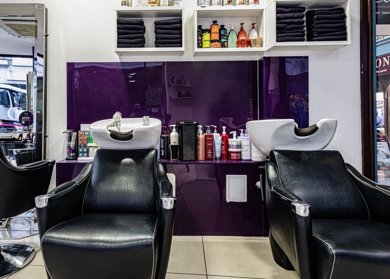 Cora Hair salon's stylish shampoo stations in Birmingham, England, GB with a plush purple backdrop.