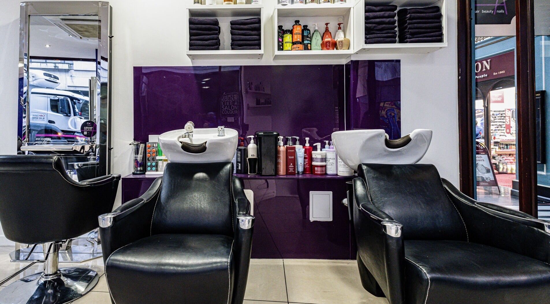 Cora Hair salon's stylish shampoo stations in Birmingham, England, GB with a plush purple backdrop.