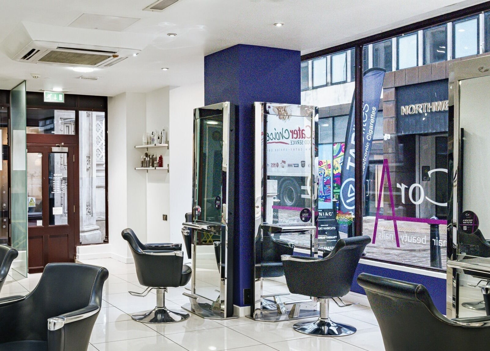 Inside Cora Hair, spacious salon in Birmingham, England, GB with modern styling chairs and wall mirrors.