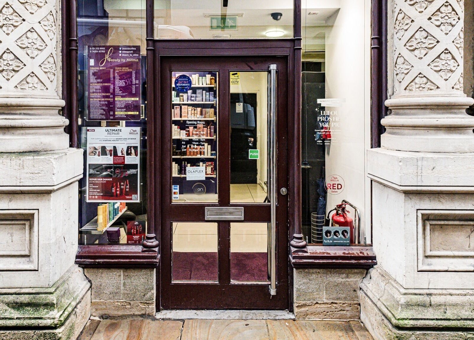 Front entrance of Cora Hair, Birmingham, England showcasing ornate columns and modern glass door.