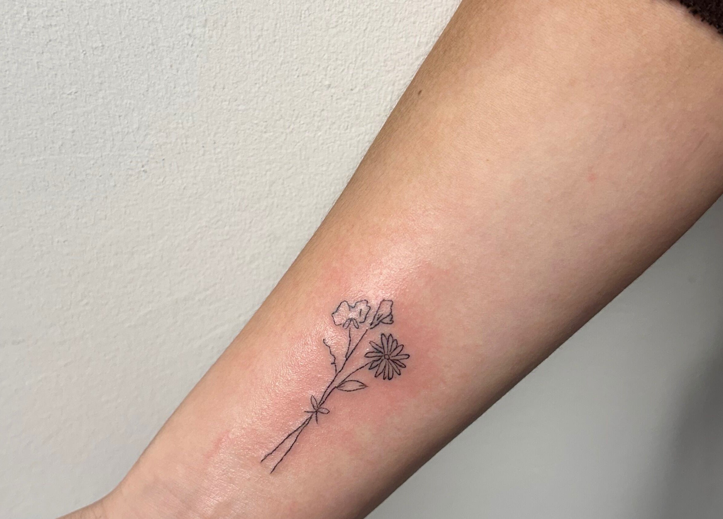 Delicate floral tattoo on arm at Sophiesticated Beauty, Thatcham, England, GB.