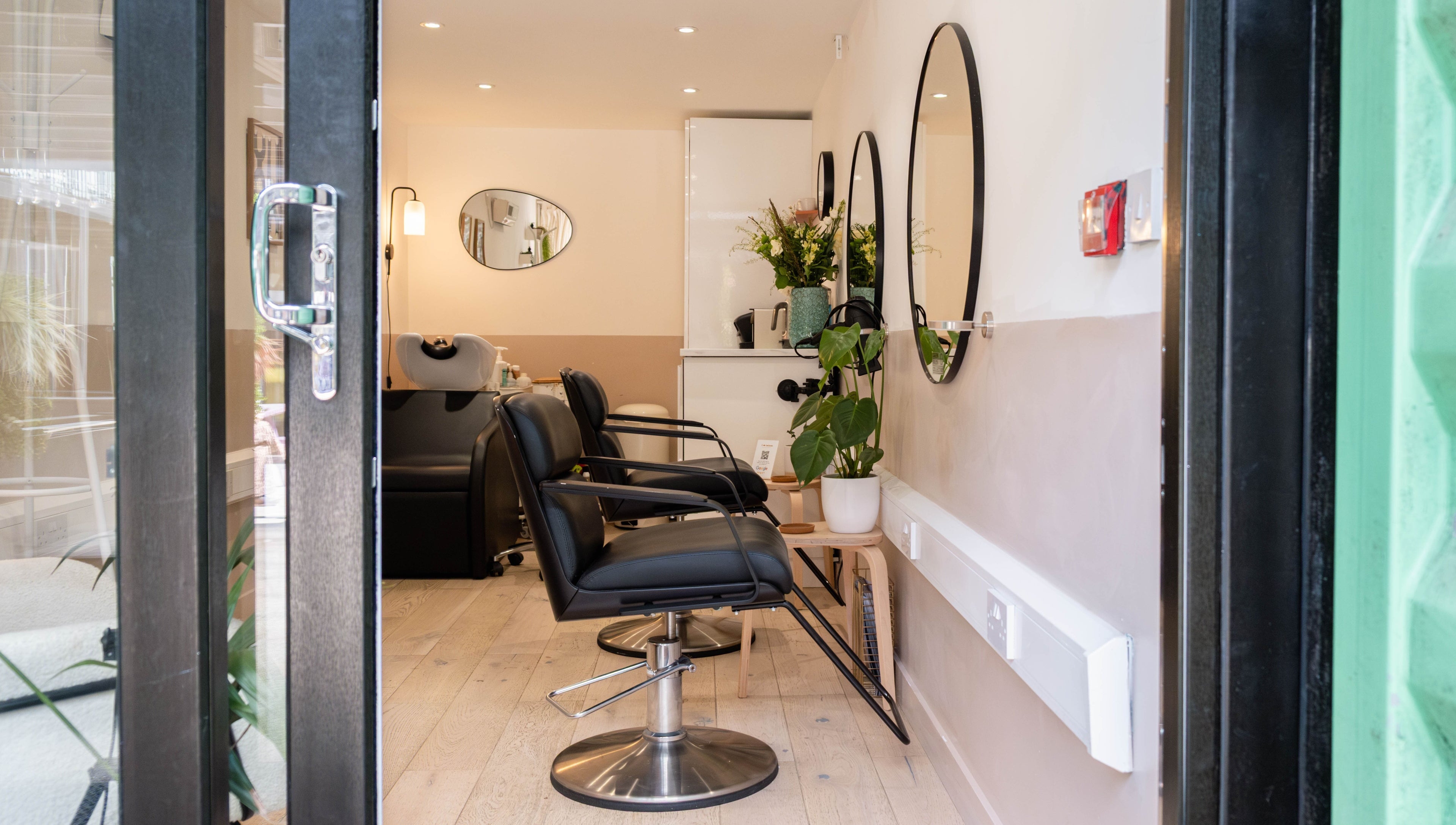Modern salon at Home of Cole Jackson, London, England, GB featuring sleek chairs and large mirrors.
