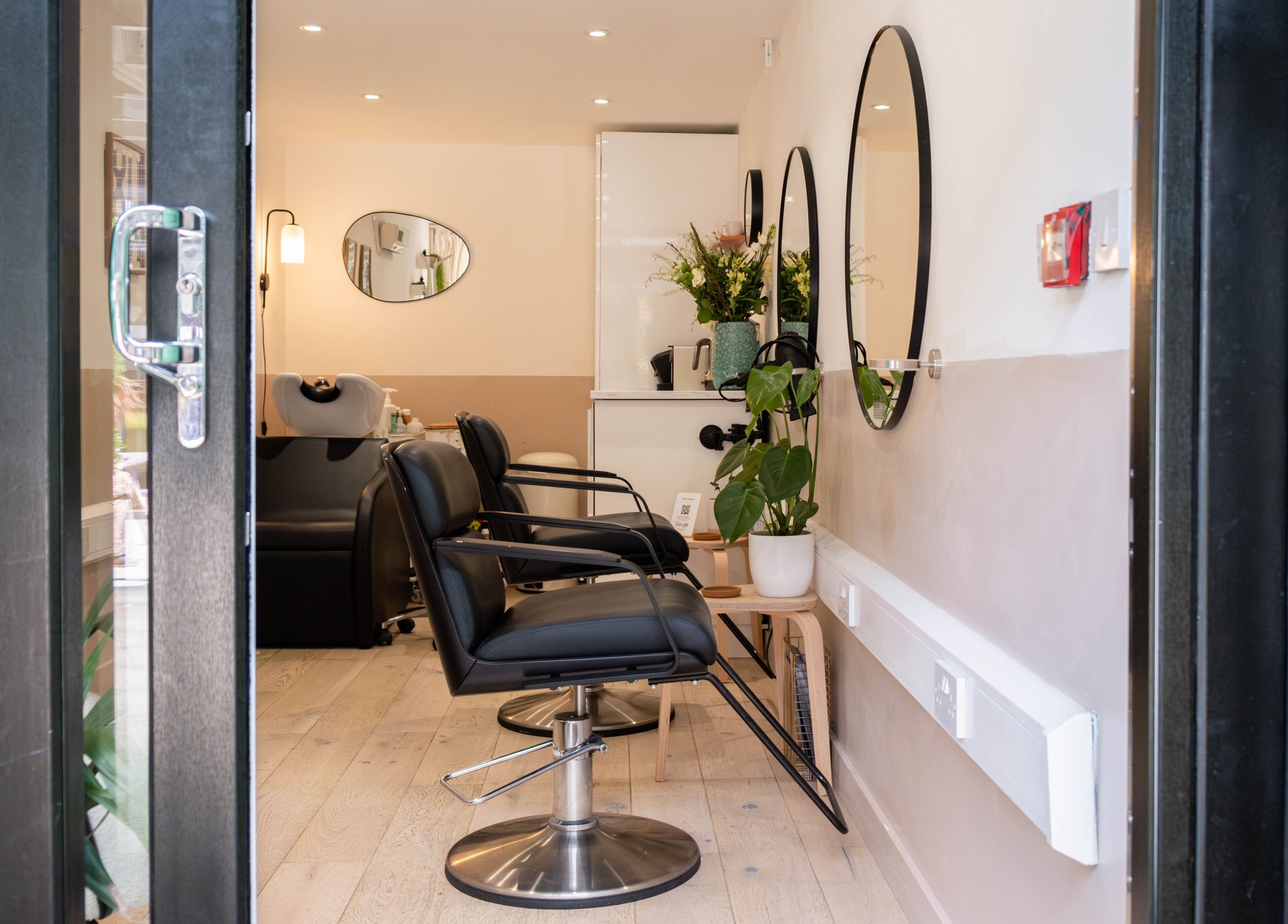Modern salon at Home of Cole Jackson, London, England, GB featuring sleek chairs and large mirrors.
