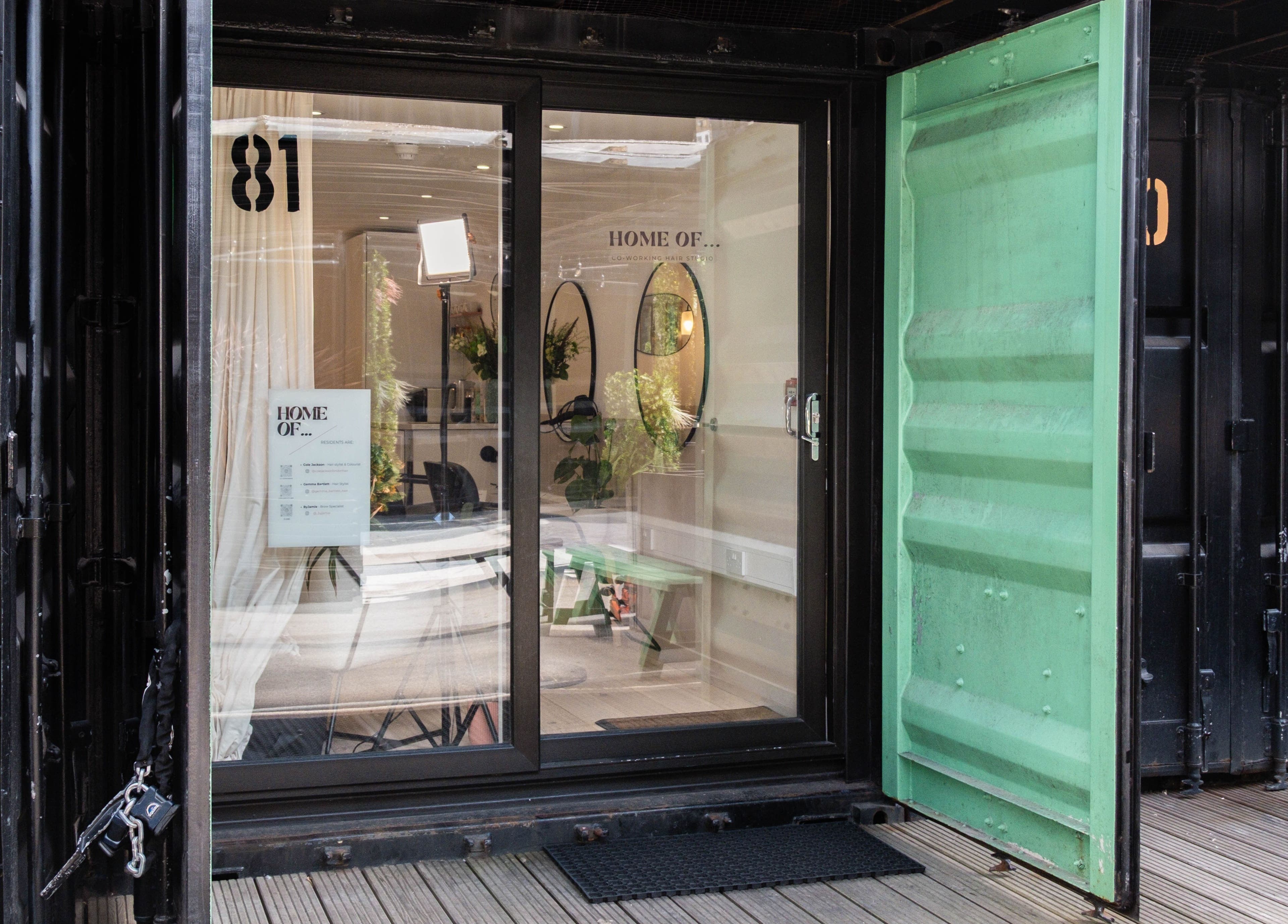 Entrance to Home of Cole Jackson studio in London, England, GB, showcasing modern glass and greenery.