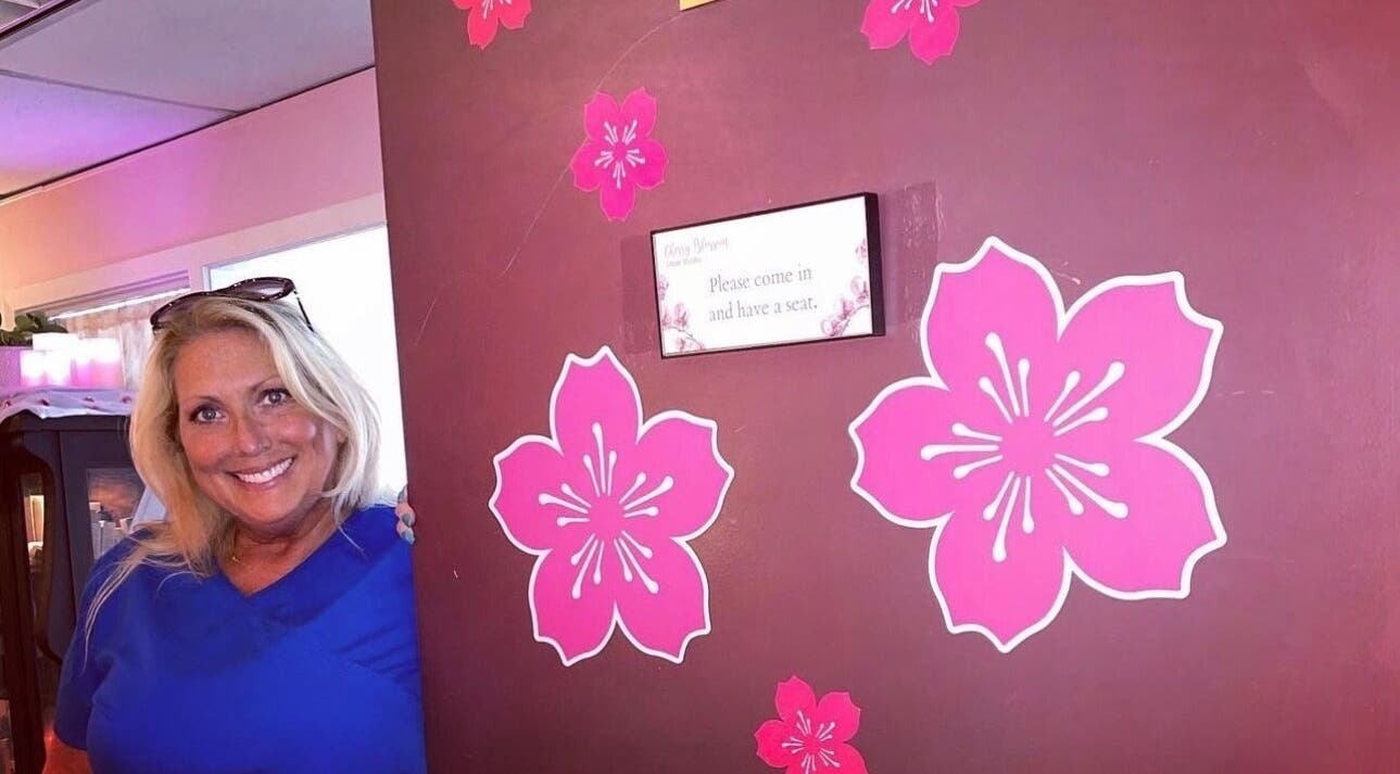 Smiling person by cherry blossom decor at Cherry Blossom Laser Studio, Fairfax, Virginia, US.