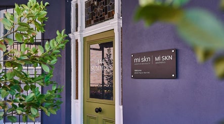 Front entrance of Mi Skn Clinic in Perth, WA, AU, with inviting green door and sign.