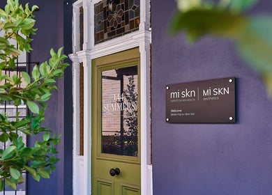 Entrance of Mi Skn Clinic in Perth, WA, AU with a welcoming door and greenery.