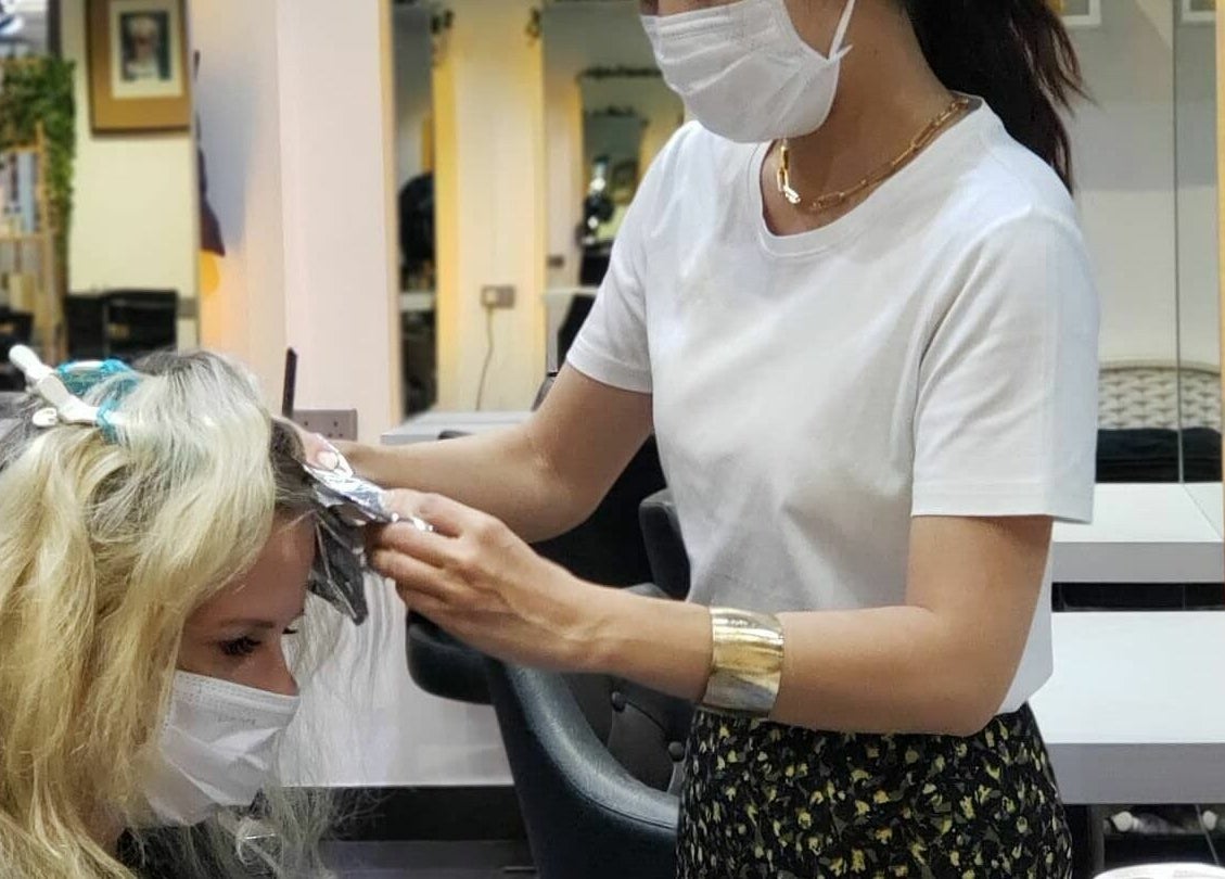 Stylist at Hair - Riffic Hong Kong Island applying hair foil with care in modern salon.