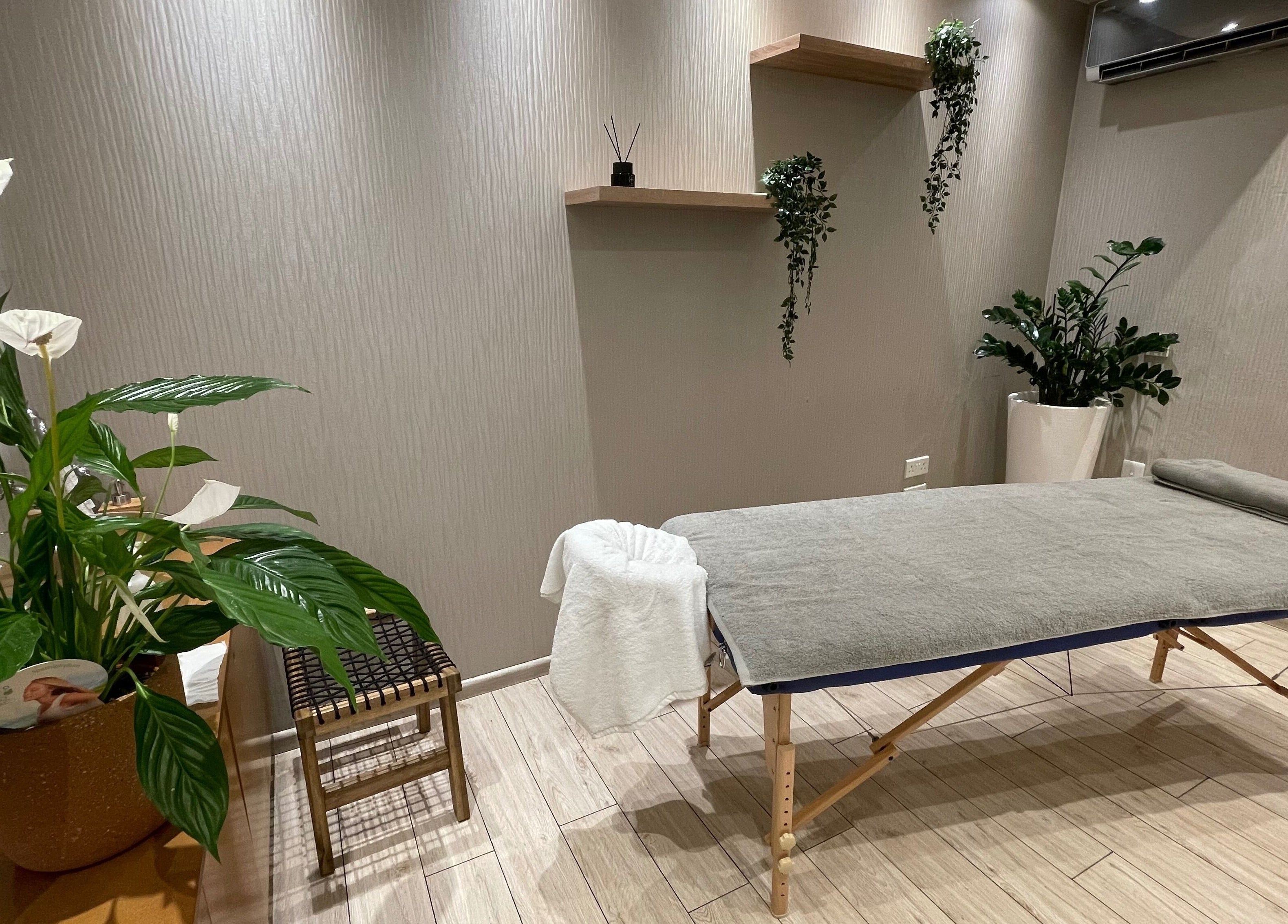 Peaceful massage room at Health First Clinic, Lemesos, Lemesos, CY with a treatment table and lush plants.