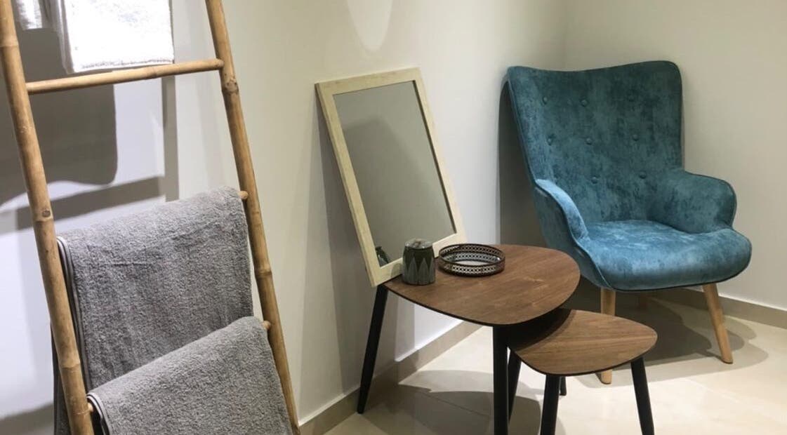 Relaxing lounge at Health First Clinic, Lemesos, Lemesos, CY with plush chair and decorative ladder.