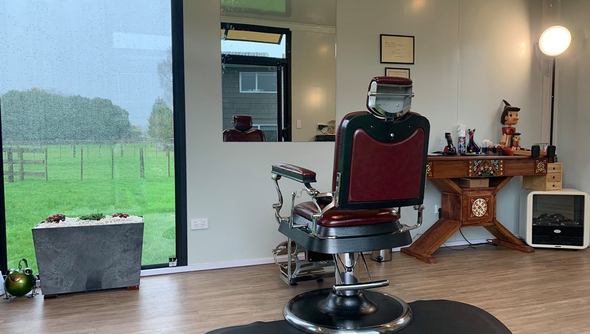 Rustic barber chair at Kaska Kuts Barber, Hamurana, Bay of Plenty, NZ overlooking a scenic outdoor view.