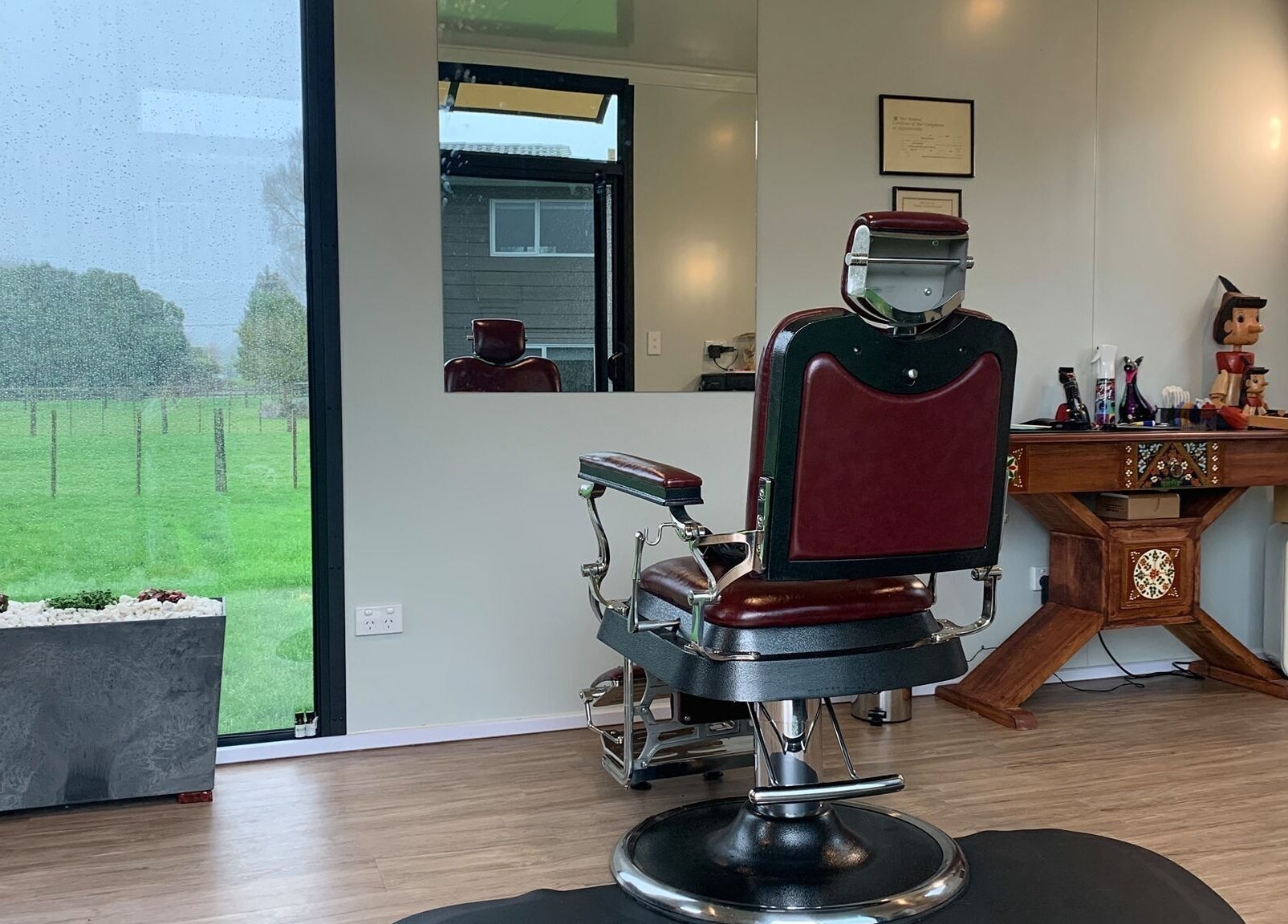 Rustic barber chair at Kaska Kuts Barber, Hamurana, Bay of Plenty, NZ overlooking a scenic outdoor view.