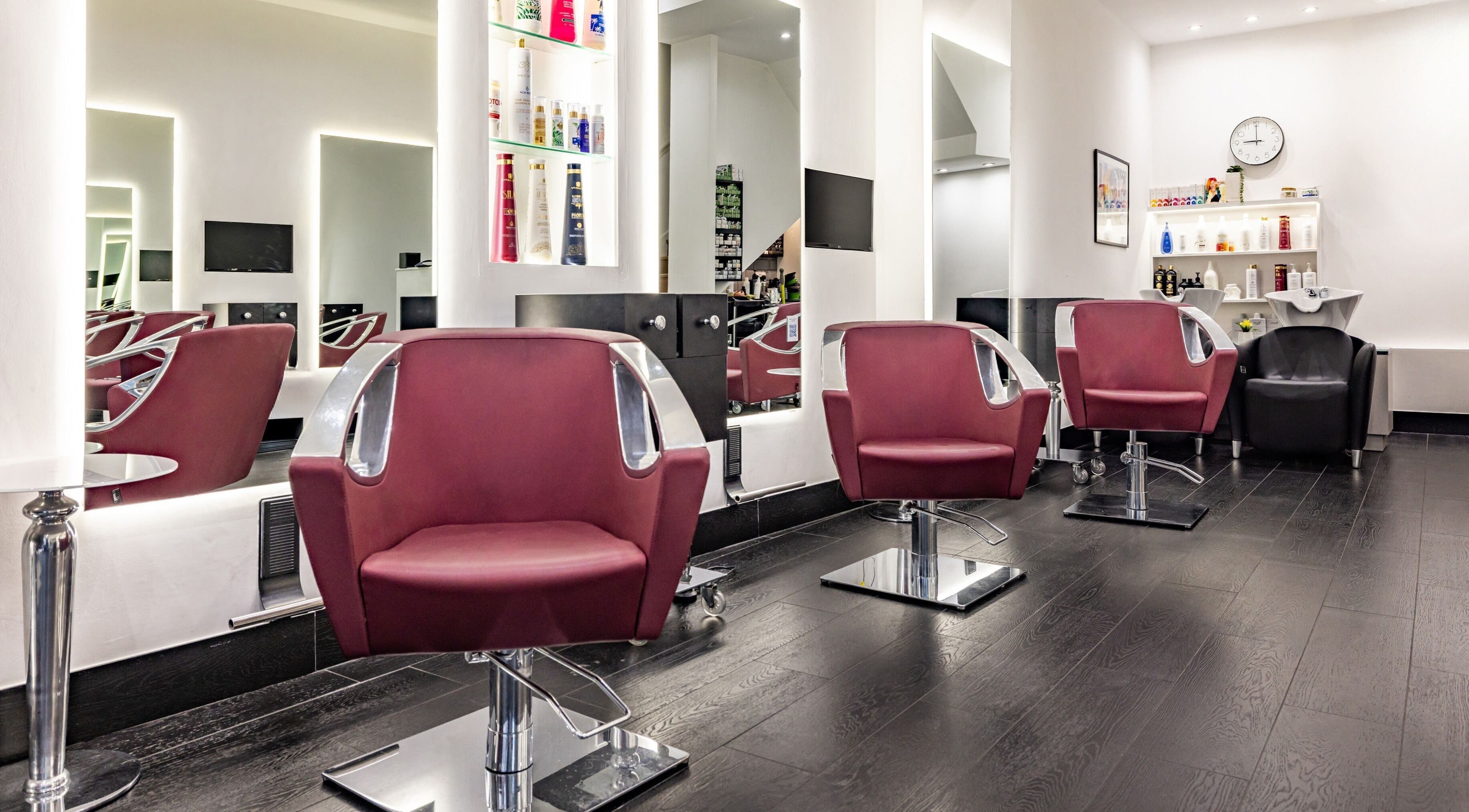 Modern salon interior at A&G Hairdressing, Kingston upon Thames, England, GB featuring sleek burgundy chairs.