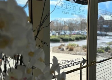Entrance of Colored by Megan in Charlotte, North Carolina, US with glass doors and floral decor.