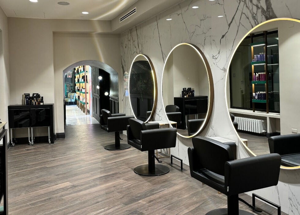 Interno moderno di Encapture - Hair Salon & More a Como, Lombardia, IT con specchi eleganti e sedie nere.