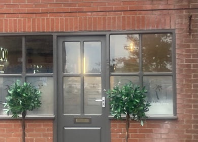 Front view of Shades, a beauty venue in Dereham, England, GB, showcasing its brick facade and elegant potted plants.