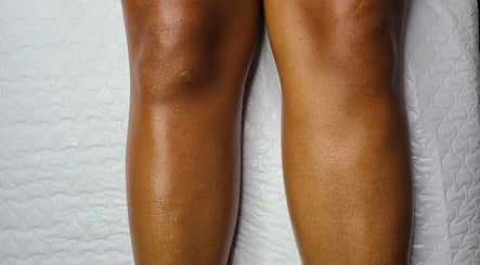 Smooth, moisturized legs showcased on a white quilt at Necessities Beauty Studio, Mandeville, Manchester Parish, JM.