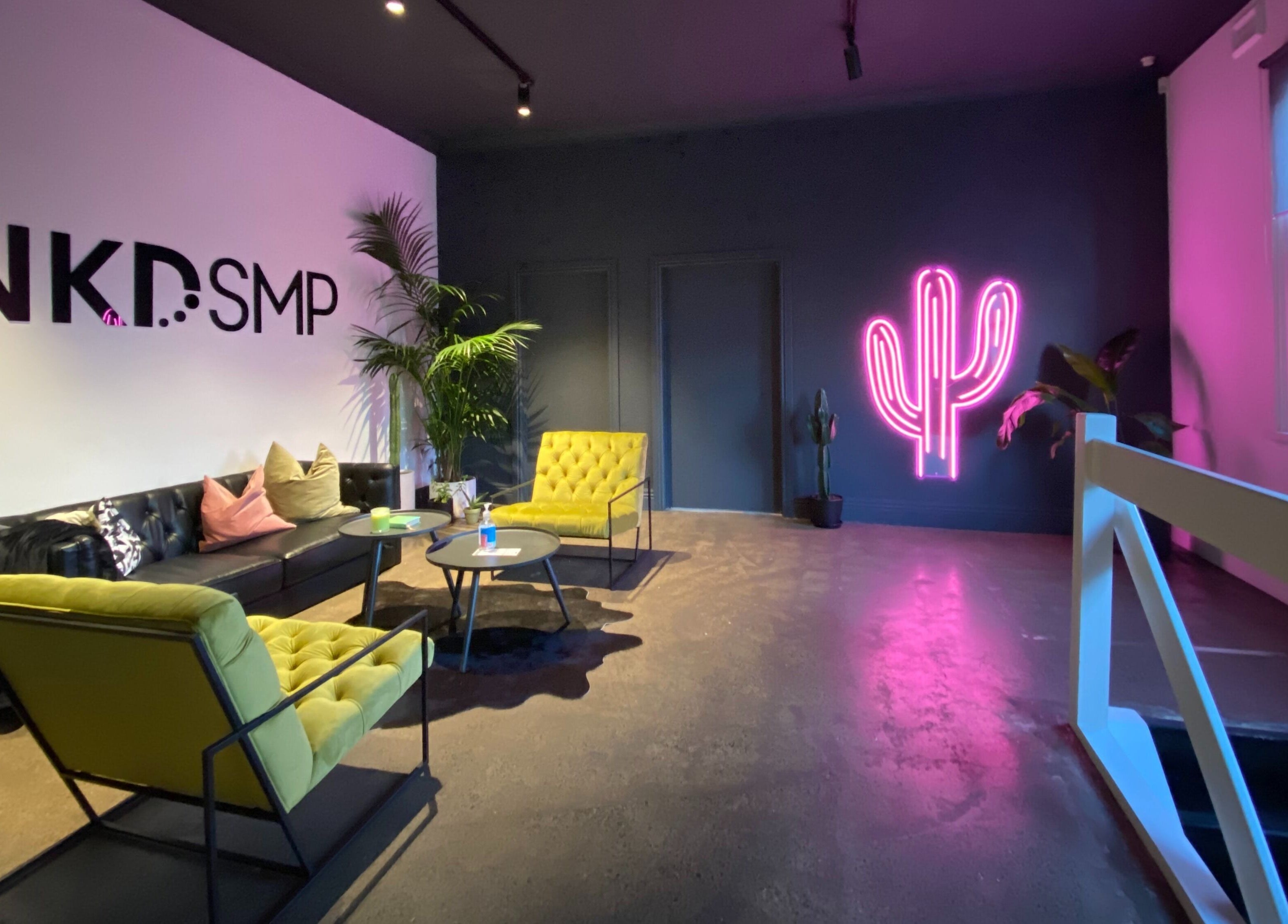 Modern lounge at Inkd SMP, Melbourne, Victoria, AU with neon cactus light and stylish seating.