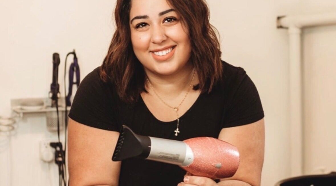 Smiling hair stylist at Cabral Beauty in Bradford West Gwillimbury, Ontario, CA, holding a blow dryer.