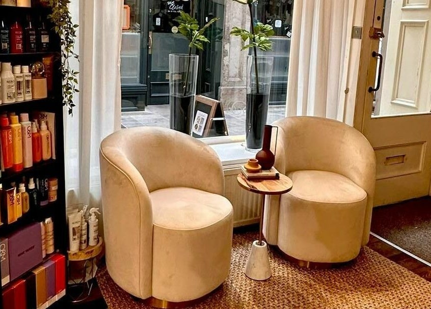 Chic salon seating at David Sebastian, Derby, England, GB. Features plush chairs, a small table, and product display.