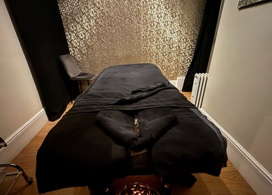 Tranquil massage room at Beauty Within, Gosport, England, GB with plush black linens and soft lighting.
