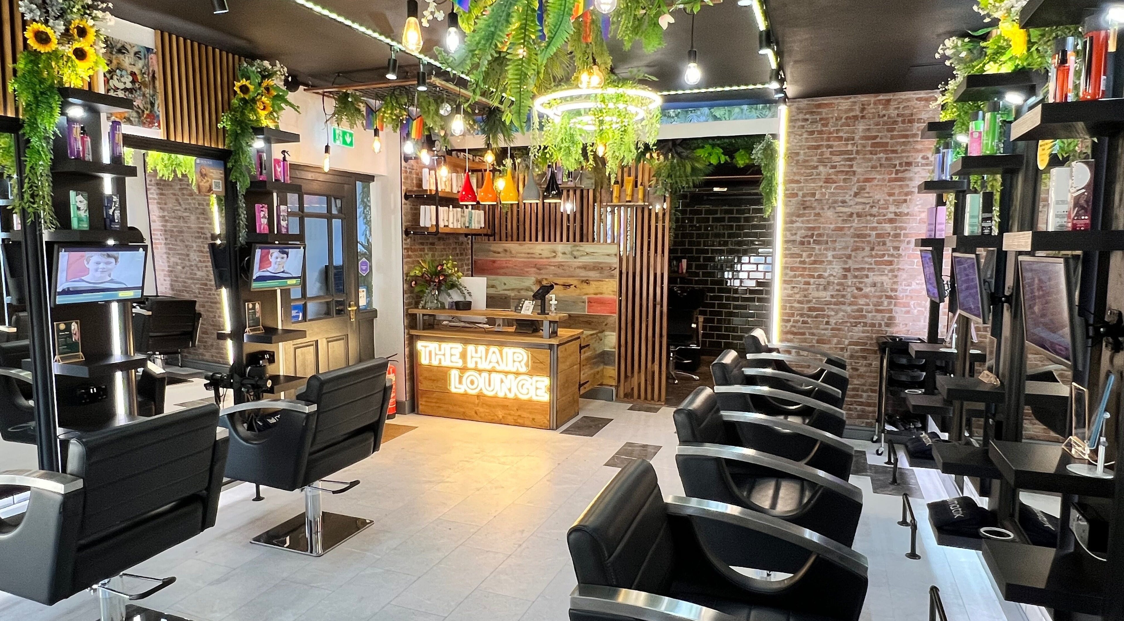 Modern interior of The Hair Lounge Bensons Court in Chepstow, Wales, GB, featuring stylish black chairs and vibrant decor.