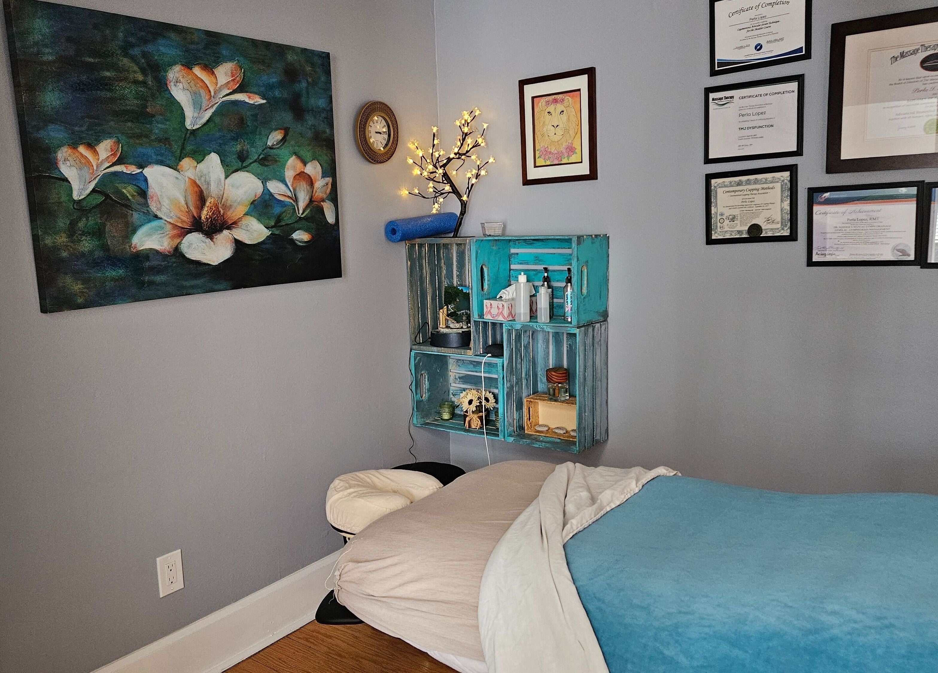 Cozy massage room at Natera Massage and Esthetics in Winnipeg, Manitoba, CA, adorned with certificates and floral decor.