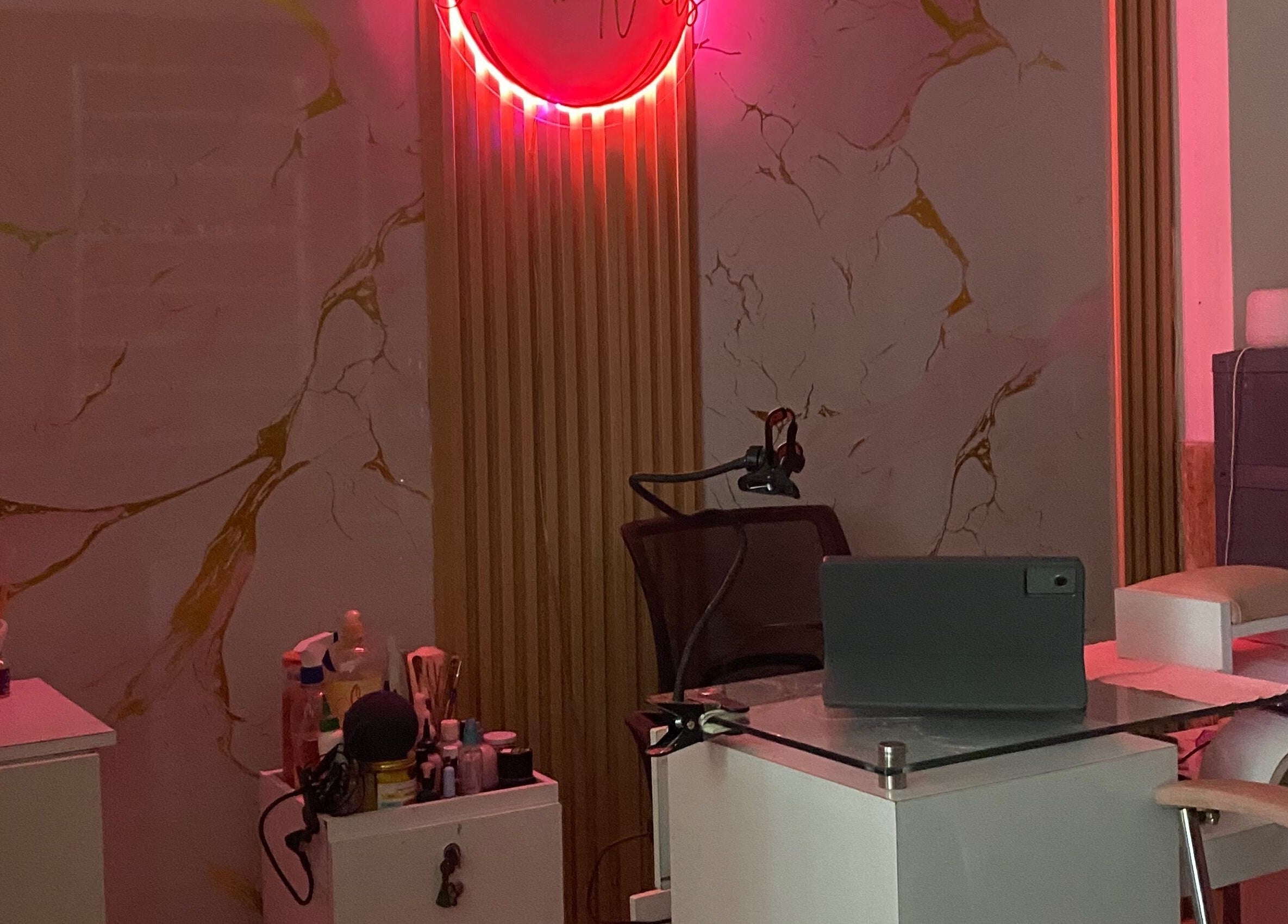 Mesa de manicura iluminada en Yulieth Nails, Buenaventura, Valle del Cauca, CO, con decoración elegante y neón rosa.