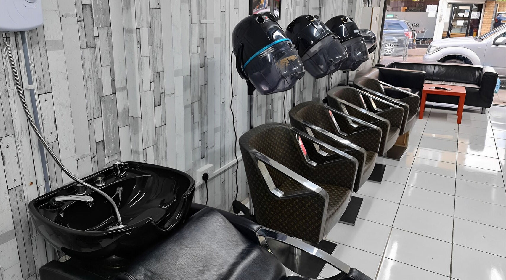 Stylish seating at Adiscolocstylist in Peckham, United Kingdom, GB, featuring modern salon chairs and washbasin.