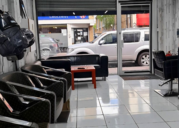 Modern seating area inside Adiscolocstylist in Peckham, United Kingdom, GB, with stylish chairs and hair dryers.
