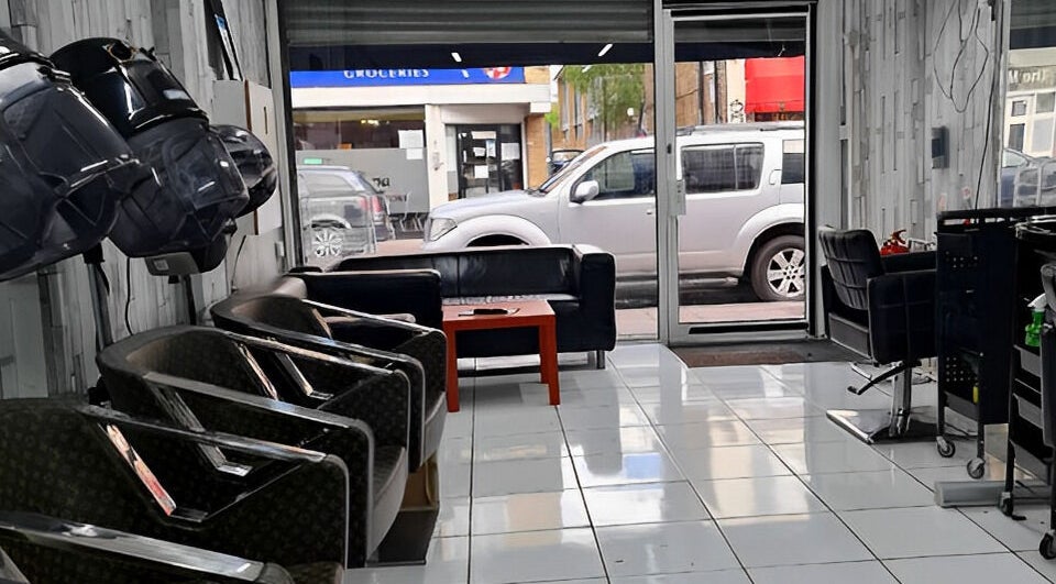 Modern seating area inside Adiscolocstylist in Peckham, United Kingdom, GB, with stylish chairs and hair dryers.