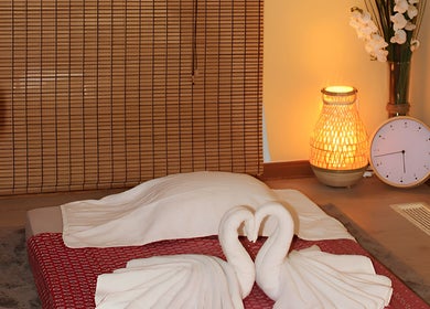Relaxing Thai massage room at Wairua Thai Masszazs Szalon, Budapest, Magyar, HU, with swan towels and warm lighting.