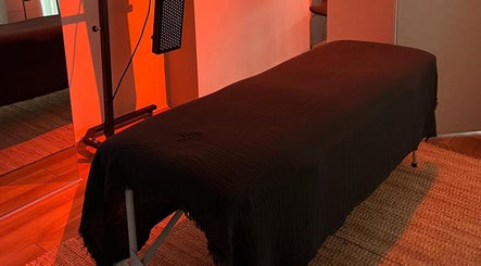 Relaxing treatment room at Saunapod, Falmouth, England, GB, with a cozy massage table under warm lighting.