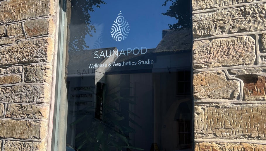 Entrance window of SAUNAPOD wellness studio, Falmouth, England, GB, with brick wall reflection.