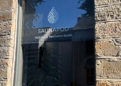 Entrance window of SAUNAPOD wellness studio, Falmouth, England, GB, with brick wall reflection.