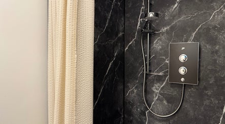 Modern shower in Saunapod, Falmouth, England, GB with black marble walls and sleek fixtures.