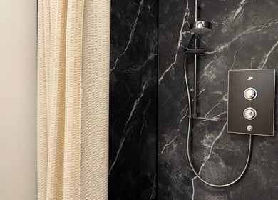 Elegant marble shower at Saunapod in Falmouth, England, GB with a modern chrome fixture.