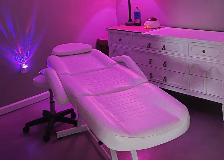 Relaxing spa room at Ramblin’ Rose Studios in Anderson, South Carolina, US with ambient pink lighting and massage bed.