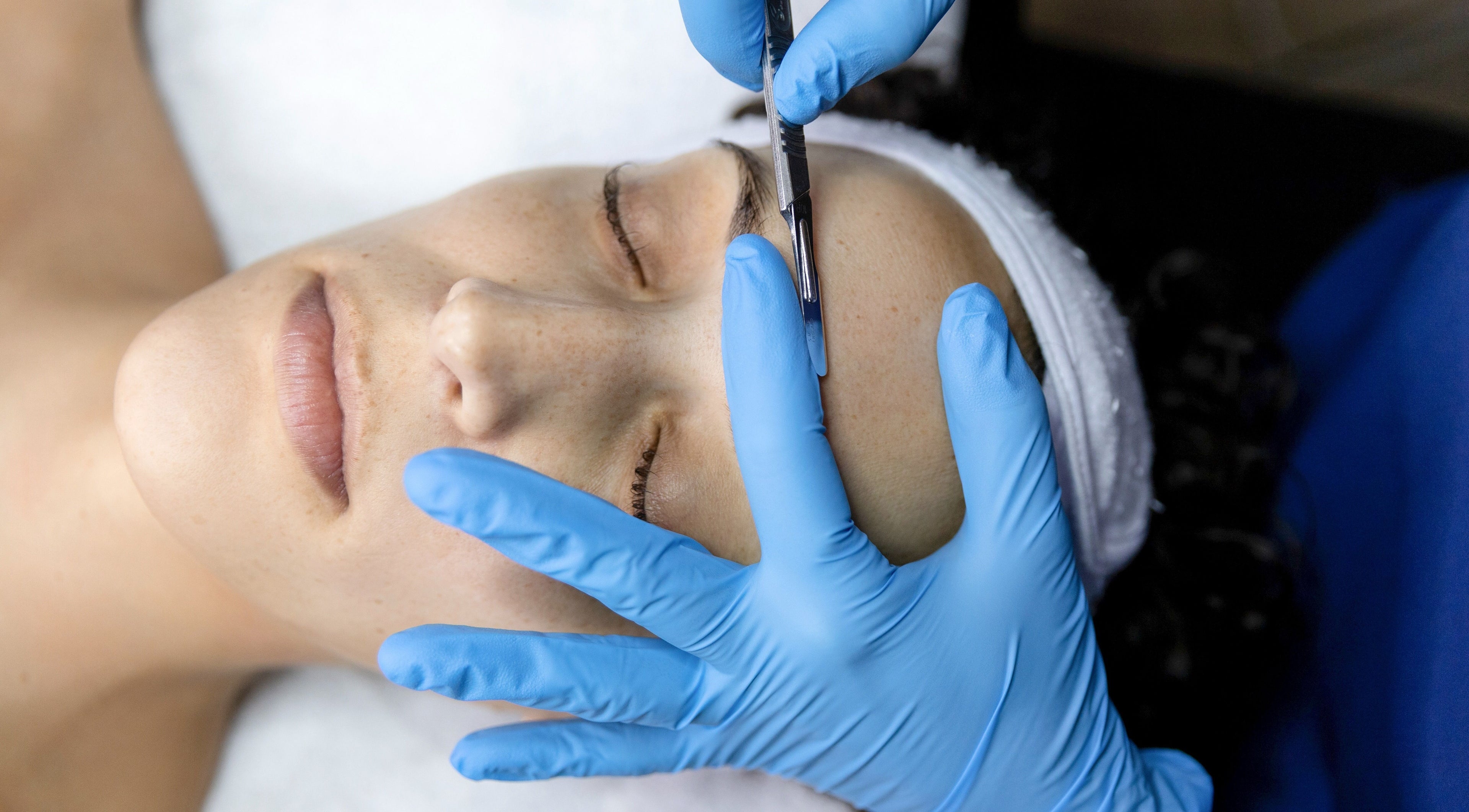 Dermaplaning at MicroMeeks Skin Studio in Port Coquitlam, British Columbia on calm client with blue gloves.
