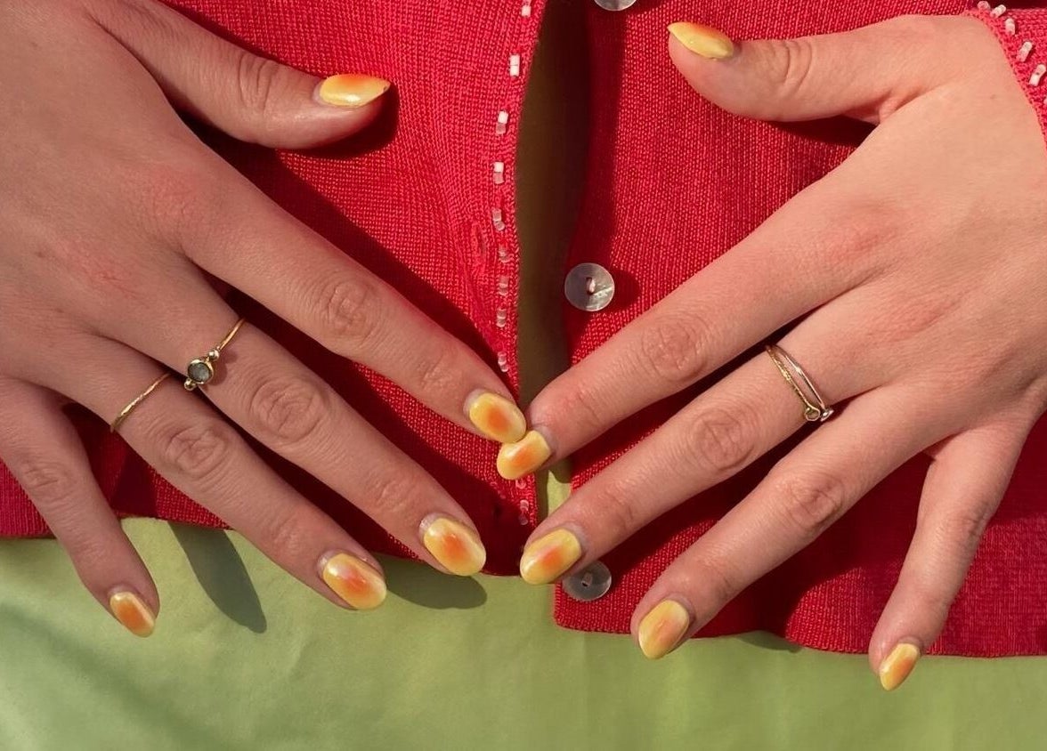 Close-up of vibrant yellow nails and rings at Thrive Studio in London, England, GB for a stylish look.